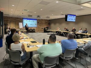 Audience sitting at a U-shaped table listening to the presenter.